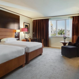 Room with two twin beds at the Hyatt Regency Kyiv with a work desk and an armchair by the window