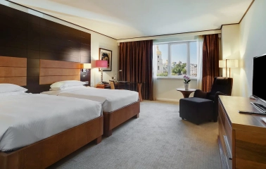 Room with two twin beds at the Hyatt Regency Kyiv with a work desk and an armchair by the window
