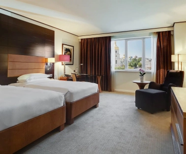 Room with two twin beds at the Hyatt Regency Kyiv with a work desk and an armchair by the window