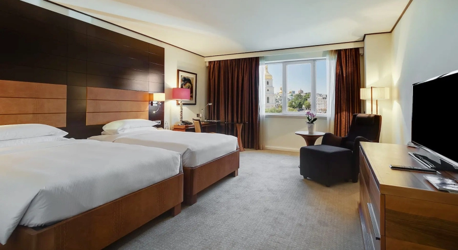 Room with two twin beds at the Hyatt Regency Kyiv with a work desk and an armchair by the window