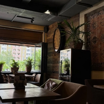 Chachapuri in Kyiv - dining corner with wall carpet, large clock and open window