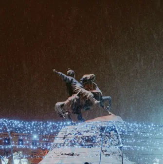 Monument to Bogdan Khmelnytsky in Kyiv - illuminated equestrian statue standing above festive Christmas lights on a snowy night