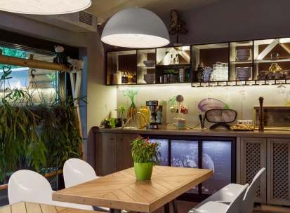 Ulyublenyi Diadia – cozy dining area with plants and open kitchen shelves