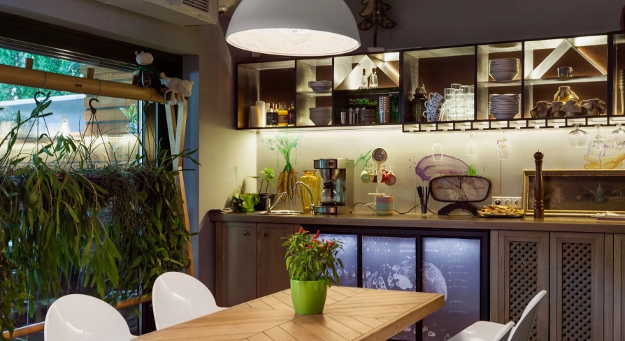 Ulyublenyi Diadia – cozy dining area with plants and open kitchen shelves
