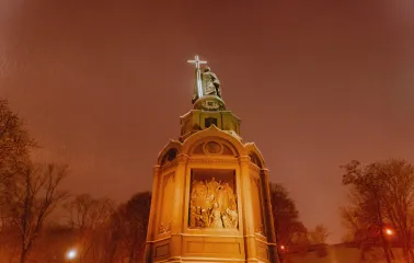 Monument to Vladimir the Great - illuminated statue holding a glowing cross on a snowy winter night