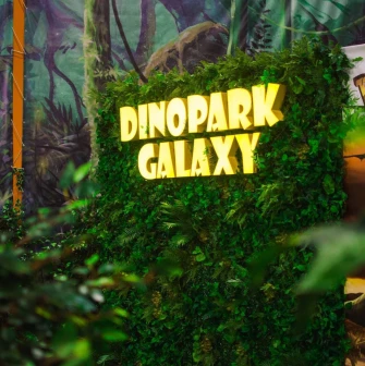 Green photo zone with a glowing Dinopark Galaxy sign in Lavina Mall