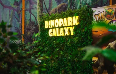 Green photo zone with a glowing Dinopark Galaxy sign in Lavina Mall
