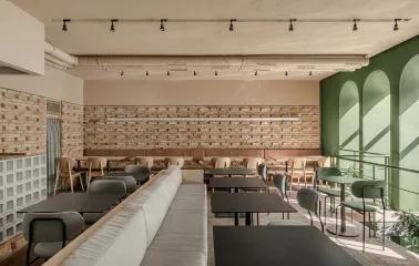 Dining space with distinctive green arched windows and soft daylight
