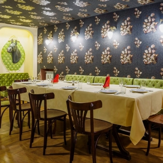Restaurant Za Dvoma Zaicyamy - private dining room with long table green velvet seats and wall decor