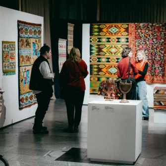 Ukrainskyi Dim in Kyiv - visitors viewing colorful traditional carpets and ceramic menorahs at an exhibition