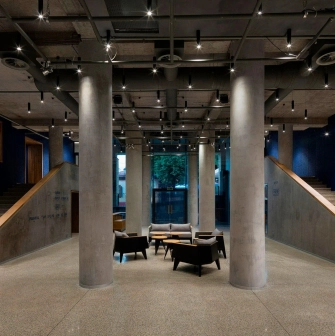 Teatr na Podoli in Kyiv - minimalist theater lobby interior with raw concrete columns, blue walls, and modern lounge seating
