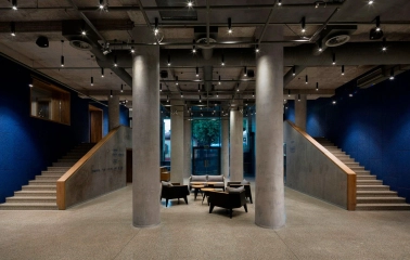 Teatr na Podoli in Kyiv - minimalist theater lobby interior with raw concrete columns, blue walls, and modern lounge seating
