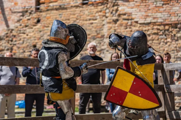 Medieval knights in full armor jousting on horseback during the IMCF World Championship in Kyiv, with colorful medieval banners and spectators in period costume