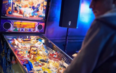 Punkraft - man playing pinball machine in neon-lit bar