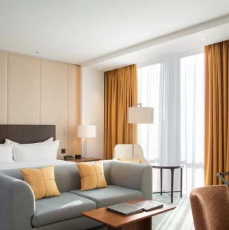 Deluxe room at Hilton Kyiv with a king-size bed, sofa and panoramic windows with yellow curtains