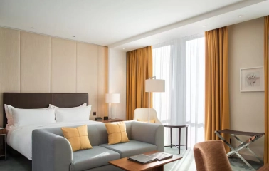 Deluxe room at Hilton Kyiv with a king-size bed, sofa and panoramic windows with yellow curtains