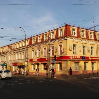 Verkhnii Val in Kyiv - sunny street corner with a yellow historical building hosting a Roshen shop