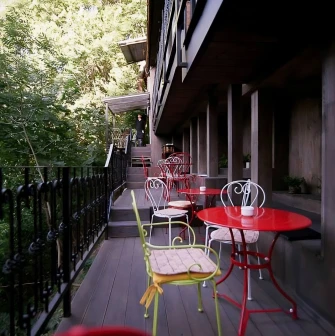 Restaurant Kanapa - narrow outdoor terrace with small tables and chairs surrounded by greenery