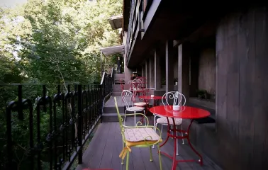 Restaurant Kanapa - narrow outdoor terrace with small tables and chairs surrounded by greenery
