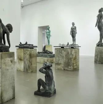 Muzei Suchasnoho Mystetstva in Kyiv - bright gallery hall displaying a collection of modern bronze sculptures on rough stone pedestals