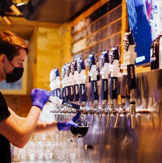 Pub Varvar bar - bartender standing behind the bar preparing drinks with tap handles visible