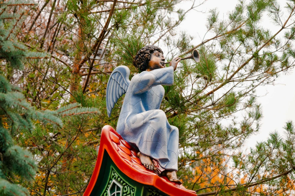 Angel sculpture with a trumpet among pine trees at Landscape Alley in Kyiv