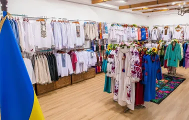 Narodnyi Dim Ukraina in Kyiv - bright spacious hall filled with racks of white and colorful embroidered shirts next to a Ukrainian flag
