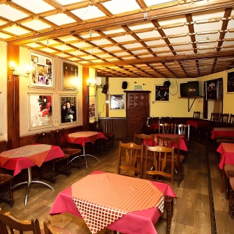 Teatr Koleso in Kyiv - cafe-style theater hall featuring wooden tables with red tablecloths and wall posters