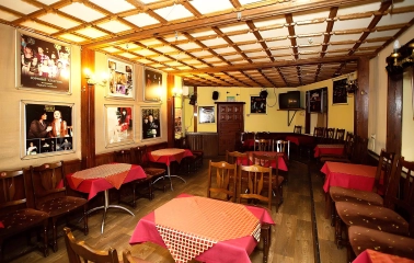 Teatr Koleso in Kyiv - cafe-style theater hall featuring wooden tables with red tablecloths and wall posters