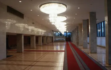 Palats Ukraina in Kyiv - spacious marble foyer with a long row of crystal chandeliers and a red carpet runner on the parquet