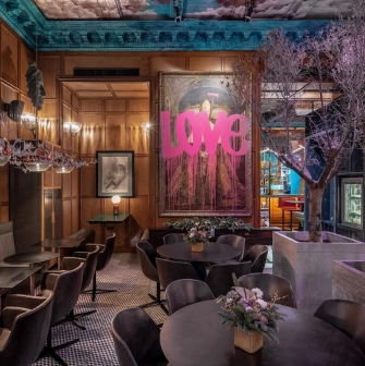 Restaurant Italiiska Redaktsiia - stylish dining room with a large LOVE painting and decorative trees