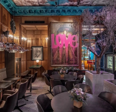 Restaurant Italiiska Redaktsiia - stylish dining room with a large LOVE painting and decorative trees