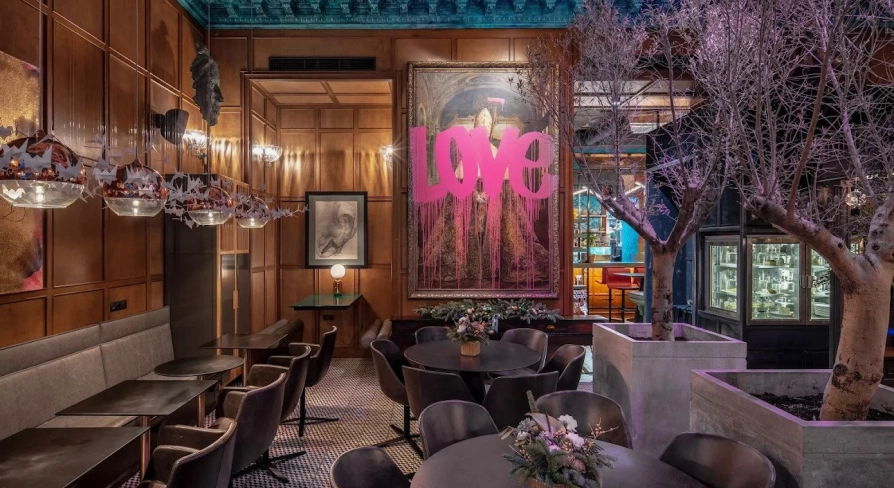 Restaurant Italiiska Redaktsiia - stylish dining room with a large LOVE painting and decorative trees