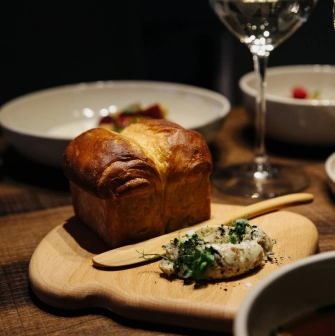 Chef’s Table — brioche bread with herb butter served on a wooden board and glass of wine