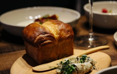 Chef’s Table — brioche bread with herb butter served on a wooden board and glass of wine