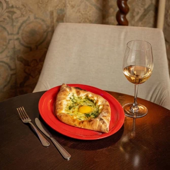 adjarian khachapuri with a raw egg and white wine glass