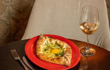adjarian khachapuri with a raw egg and white wine glass
