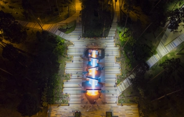 Park Partyzanskoi Slavy in Kyiv - aerial night view of the park's central alley featuring the glowing geometric fountain complex surrounded by dark forest trees