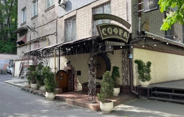 Sofra in Kyiv - restaurant entrance with forged metal arch, sign and potted plants