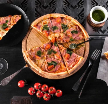 A cut pizza on a wooden board with cherry tomatoes and sauce