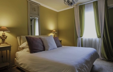 Vozdvyzhenskyi in Kyiv - bedroom suite featuring a large bed, green curtains, and vintage lamps
