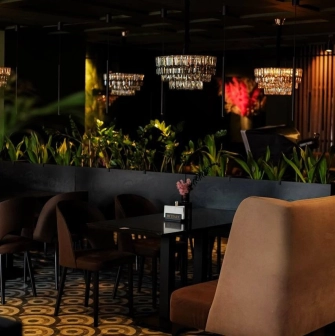 By Italy - dark interior, soft chairs and lots of greenery