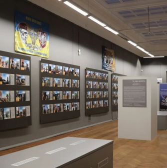 Kyivska Kartynna Halereia in Kyiv - exhibition hall with a memorial wall of photos and a military flag