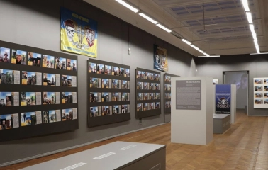 Kyivska Kartynna Halereia in Kyiv - exhibition hall with a memorial wall of photos and a military flag