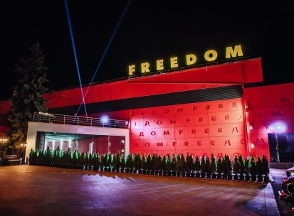 Freedom Hall in Kyiv - bright red facade with yellow neon letters and spotlights beaming into the night sky