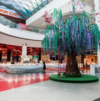 Ocean Plaza in Kyiv - large decorative artificial tree with cascading purple and green ribbons standing as a centerpiece near jewelry islands