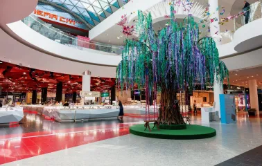 Ocean Plaza in Kyiv - large decorative artificial tree with cascading purple and green ribbons standing as a centerpiece near jewelry islands