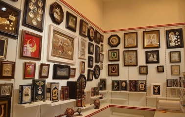 Folkmart in Kyiv - souvenir shop corner featuring a wall of framed icons and shelves with ornate books and maces