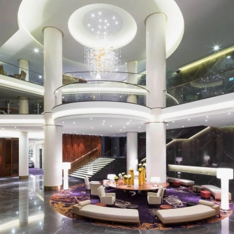 The luxurious lobby of the Hilton Kyiv Hotel with columns, a round seating area and a modern chandelier
