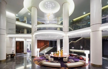 The luxurious lobby of the Hilton Kyiv Hotel with columns, a round seating area and a modern chandelier